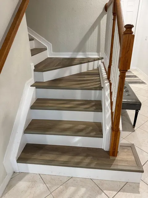 La misma escalera con escalones de vinilo color roble y contrahuellas blancas, después
